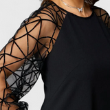 Elegante vestido negro con mangas de malla y corte holgado para un look sofisticado y cómodo