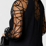 Elegante vestido negro con mangas de malla y corte holgado para un look sofisticado y cómodo